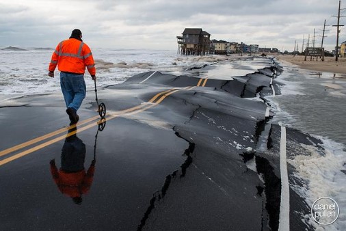 Image of N.C. 12 roads broken and buckled after a hurricane. The ocean water washed into the broken pavement.