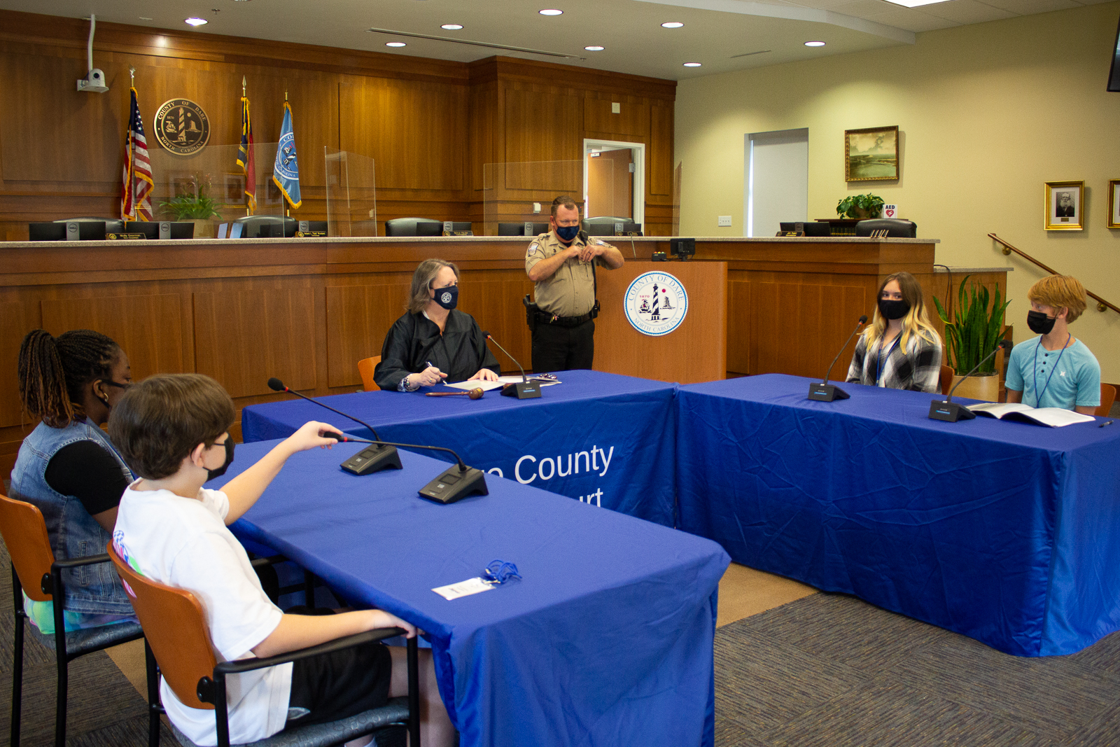 Image of teen court trial. Four students and a judge sit at tables.