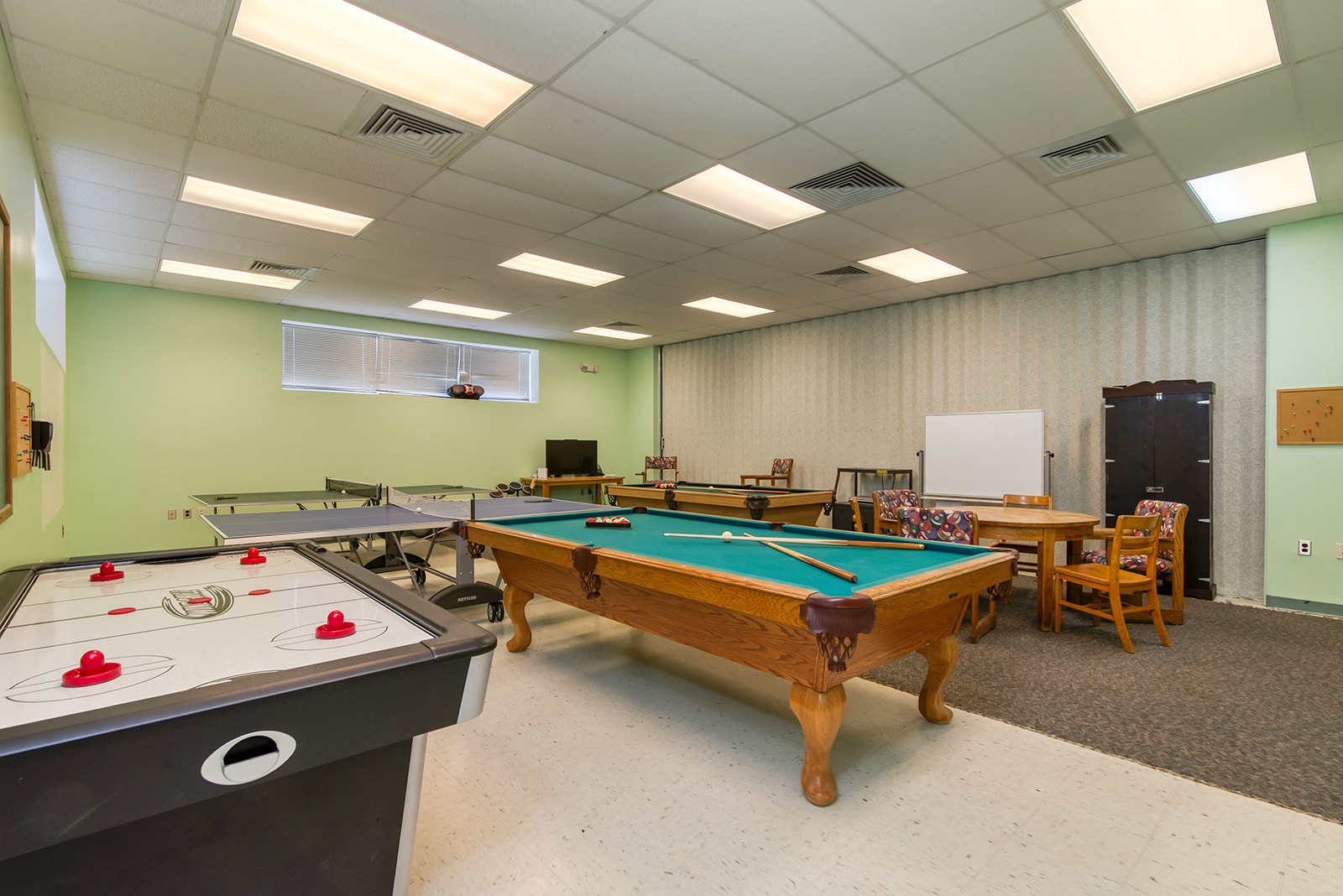 Image of a multipurpose game room with pool and air hockey tables.