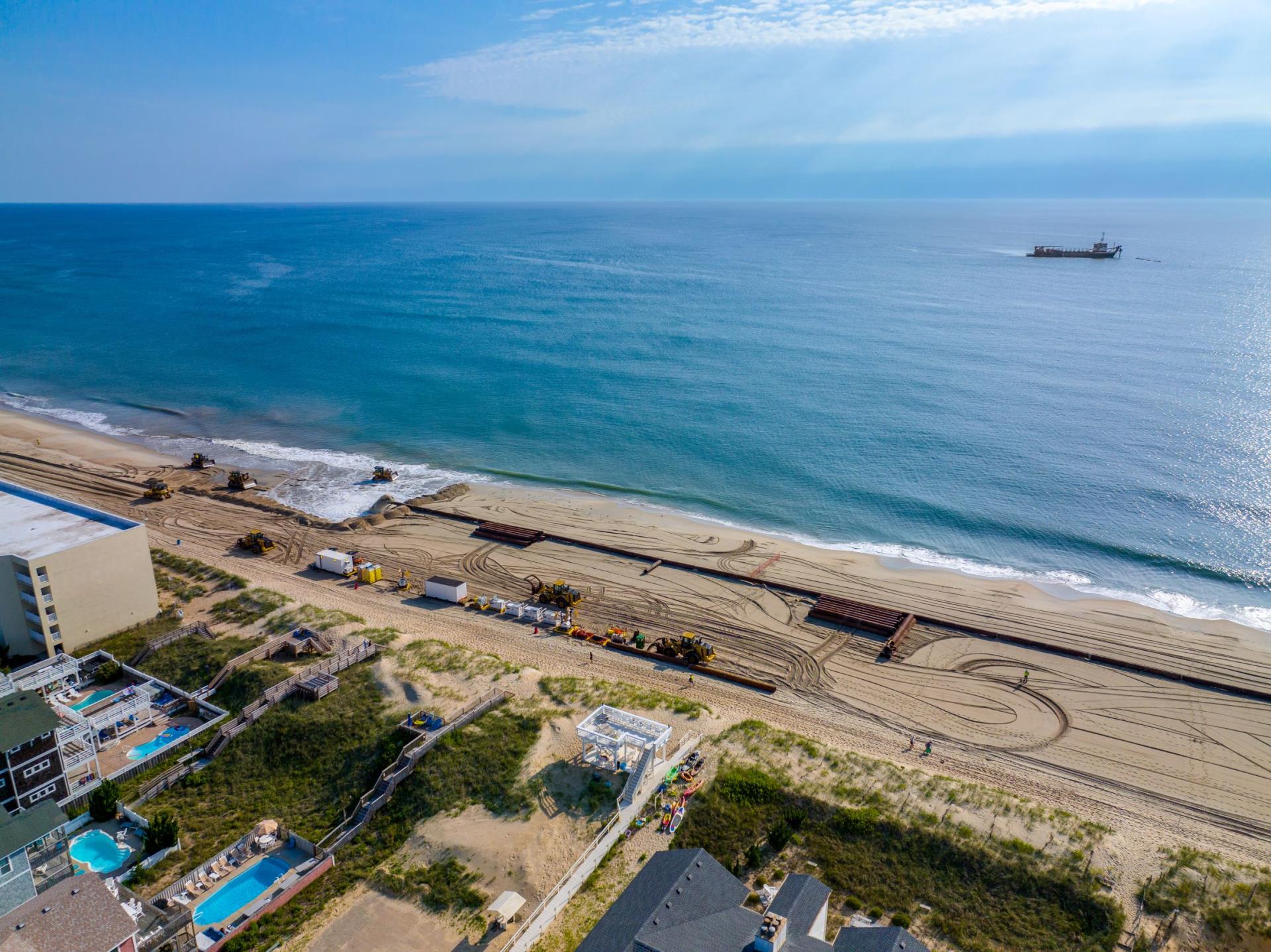 Aerial view of beach nourishment operations in Kill Devil Hills with dredge offshore