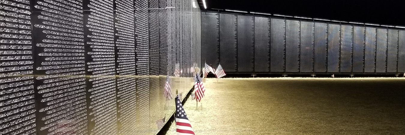 Image of The Wall That Heals at nighttime with flags set up in front of the wall.