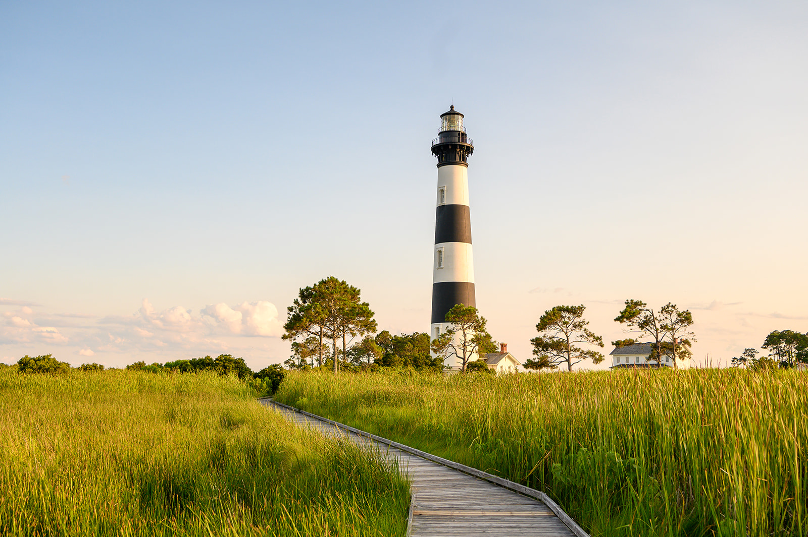Image of a pathway leading to the Bodie Island Lighthouse with marsh grasses on either side.