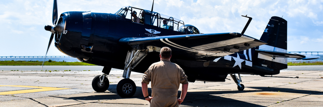 Image of a man standing in front of a WWII airplane.
