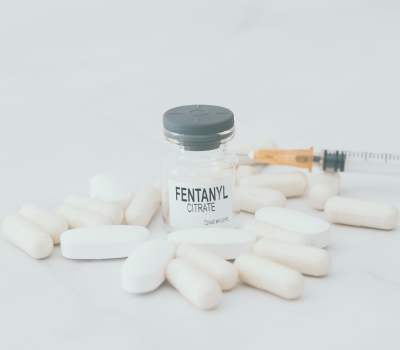 Image of fentanyl bottle and pills with syringe.