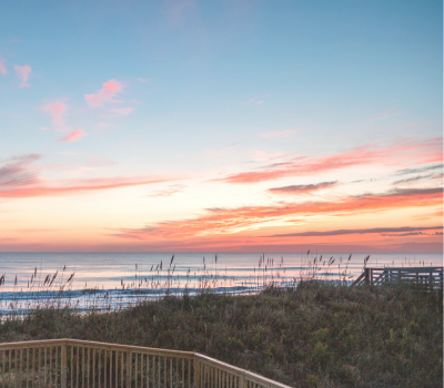 Image of walkways leading through the grassy dunes to a beach sunset.