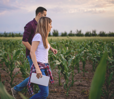 Image of a young girl walking through a corn field with an instructor holding a notepad.