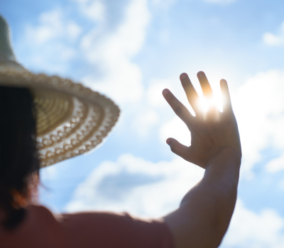 Image of a woman wearing a hat blocking the sun with her hand.