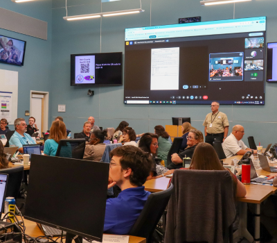 A large group of people are seated in the Emergency Operations Center for a hurricane exercise.